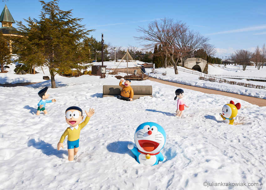 Manga character Doraemon and his friends covered in snow in a park.